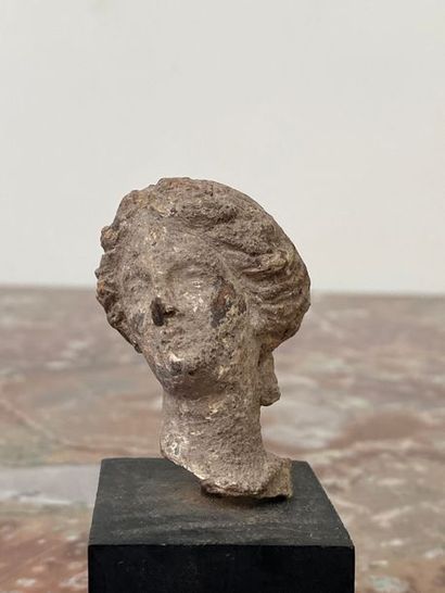 Terracotta female head, hair styled in wavy...