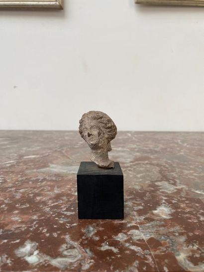 Terracotta female head, hair styled in wavy...