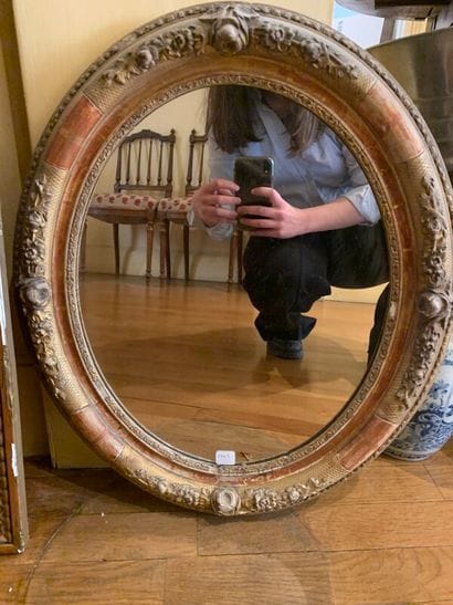Un miroir oval en bois doré à décor sculpté...