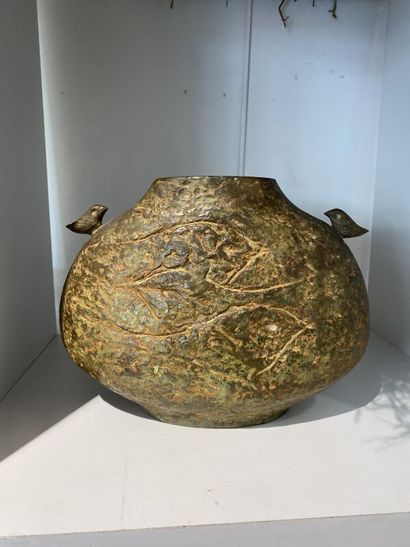 Metal vase with flat body topped by two birds...