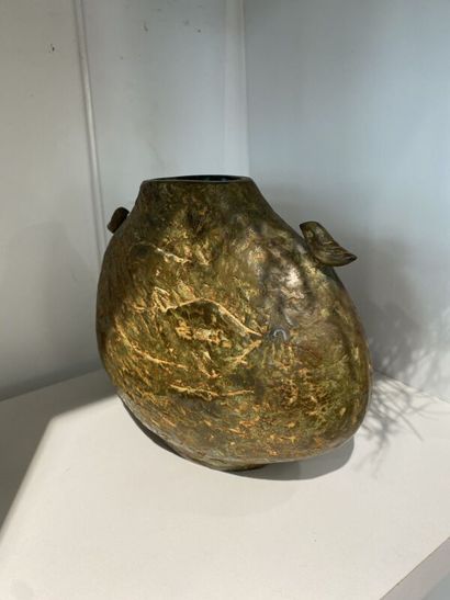 Metal vase with flat body topped by two birds...