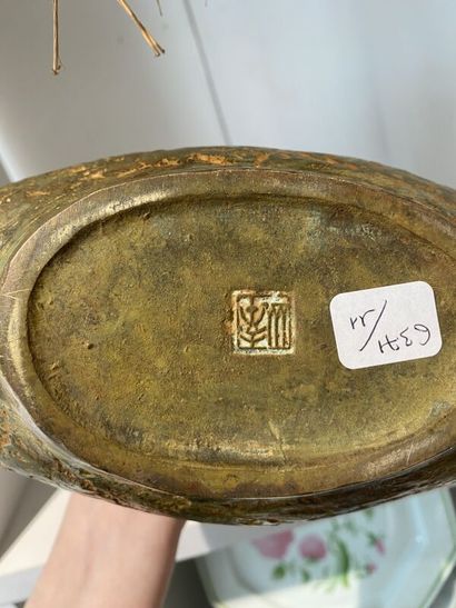 Metal vase with flat body topped by two birds...