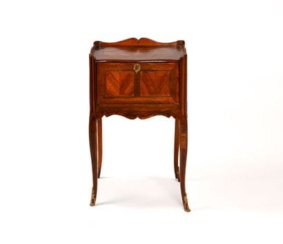A veneered wooden nightstand with a drop-down...