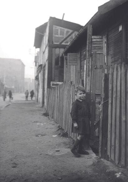 AFP

A child poses near wooden shacks in...
