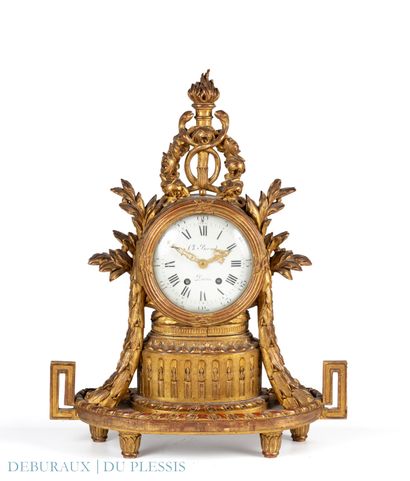 Pendule en bois sculpté et doré sommée d’un...