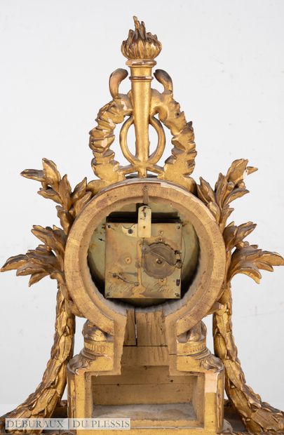 Pendule en bois sculpté et doré sommée d’un...