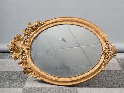 Large oval mirror in carved and gilded wood,...