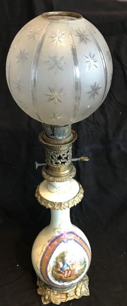 Une lampe à pétrole en porcelaine polychrome...