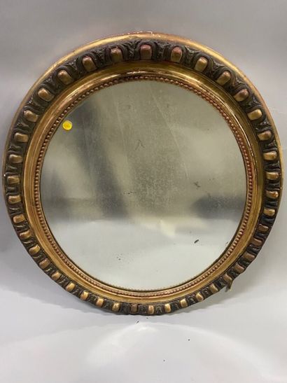 Un miroir ovale en bois stuqué doré à décor...