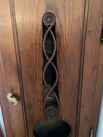 A natural wood floor clock with a PLENAHIER...