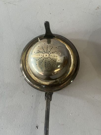 A silver-handled ladle and a silver tea strainer....