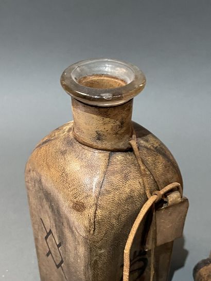 Deux bouteilles en verre gaînées de cuir...