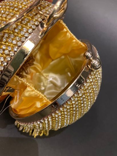 A rigid clutch bag shaped like a golden sphere,...