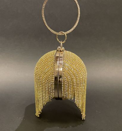 A rigid clutch bag shaped like a golden sphere,...