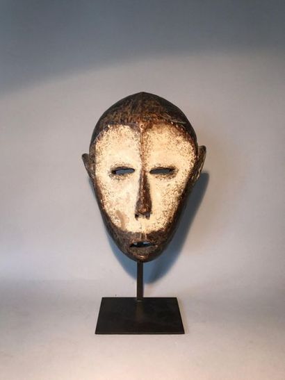 Carved wooden mask with a white crusty patina.
LEGA...