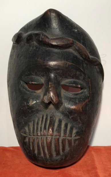 Carved wooden mask with a simian head surmounted...
