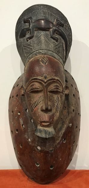 Mask in carved red wood, the cap decorated...
