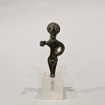 Stylized female votive statuette whose discoidal...