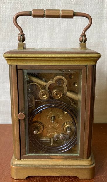 Travelling clock, the bronze cage mount surmounted...