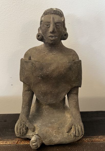Statuette in clay representing a seated character....