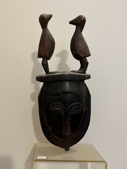 African mask in carved wood surmounted by...