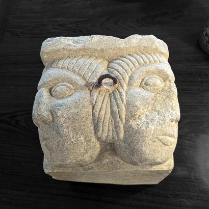 Stone modillion carved with two faces, in...