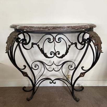 A wrought-iron console table with a scrolled...
