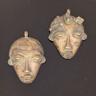 Two bronze pendants featuring African masks....