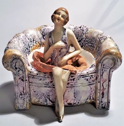 Mignonnette en porcelaine assise dans un...