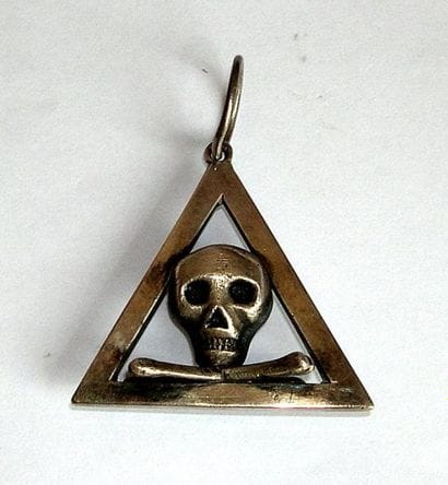 Bijou triangulaire contenant un crane reposant...