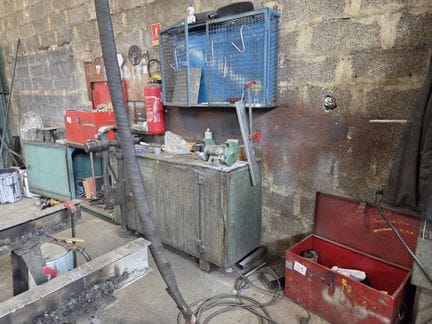 un établi métallique 2 portes, avec 1 touret + 1 étau + 2 caisses métalliques rouges comprenant des outils liés à l’acti